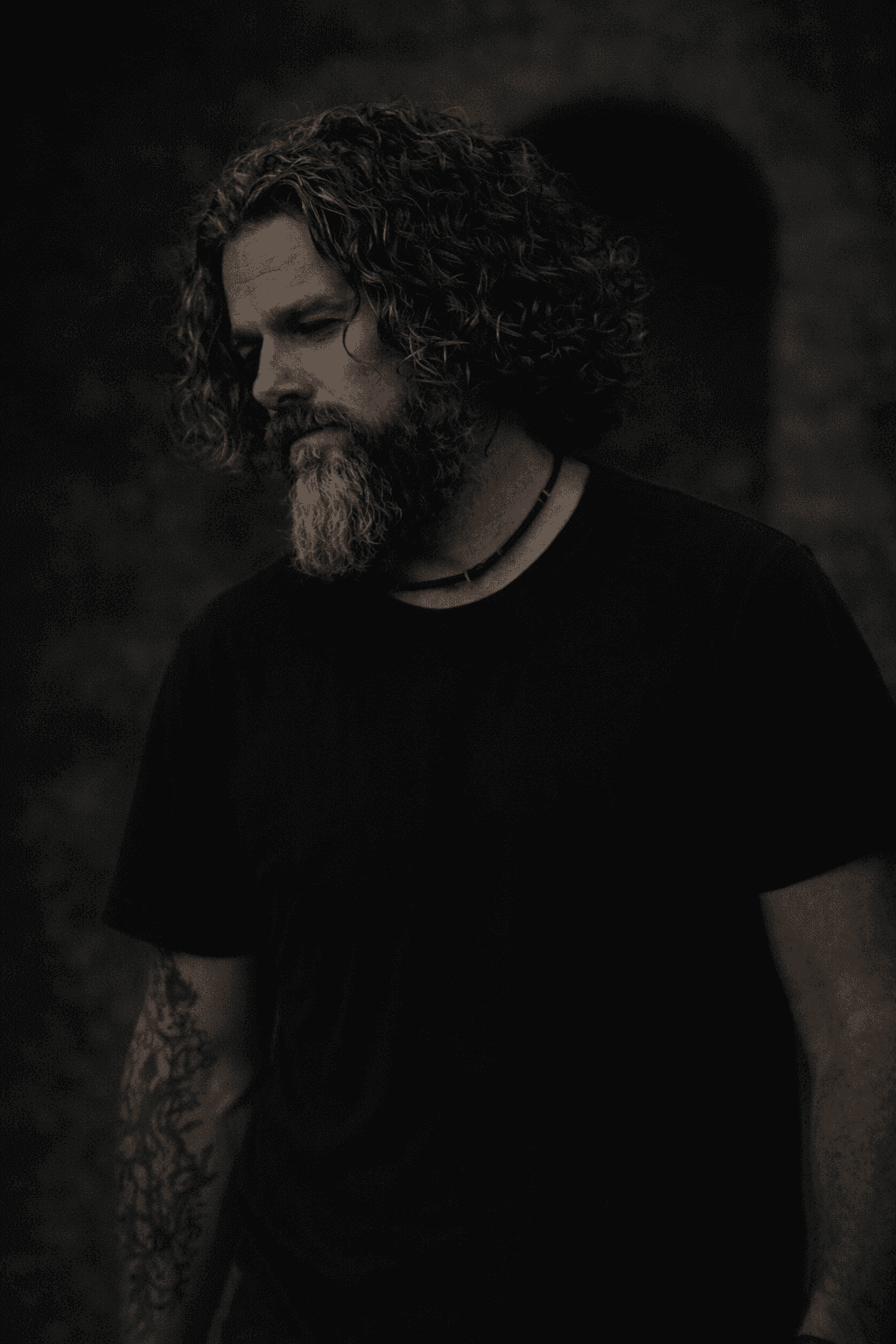 Portrait of Sir Christopher in a dark shirt, looking thoughtful in soft, moody light