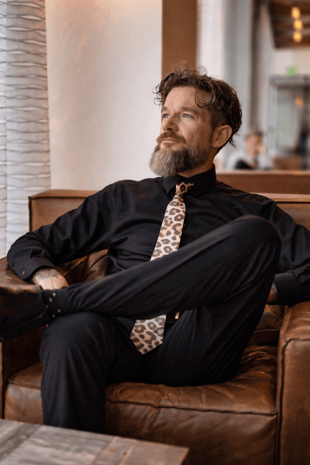 Sir Christopher relationship and power dynamics coach sitting thoughtfully in a chair looking toward natural light.